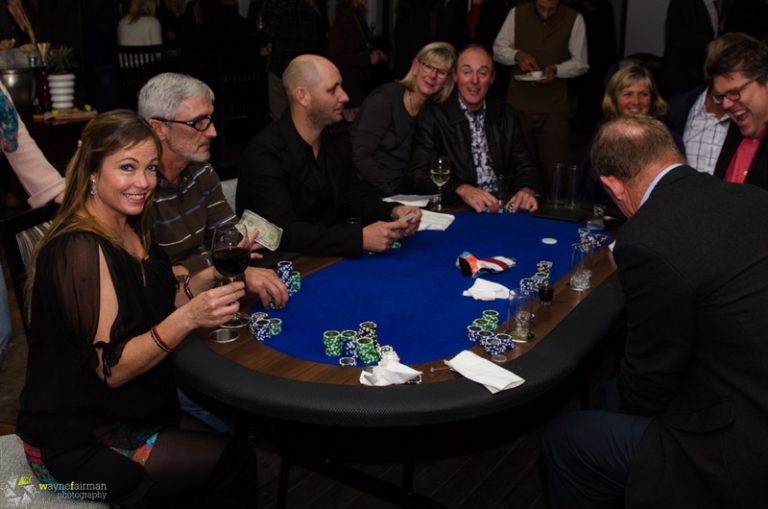 People sitting around a table, focused on playing poker with cards and chips in front of them.